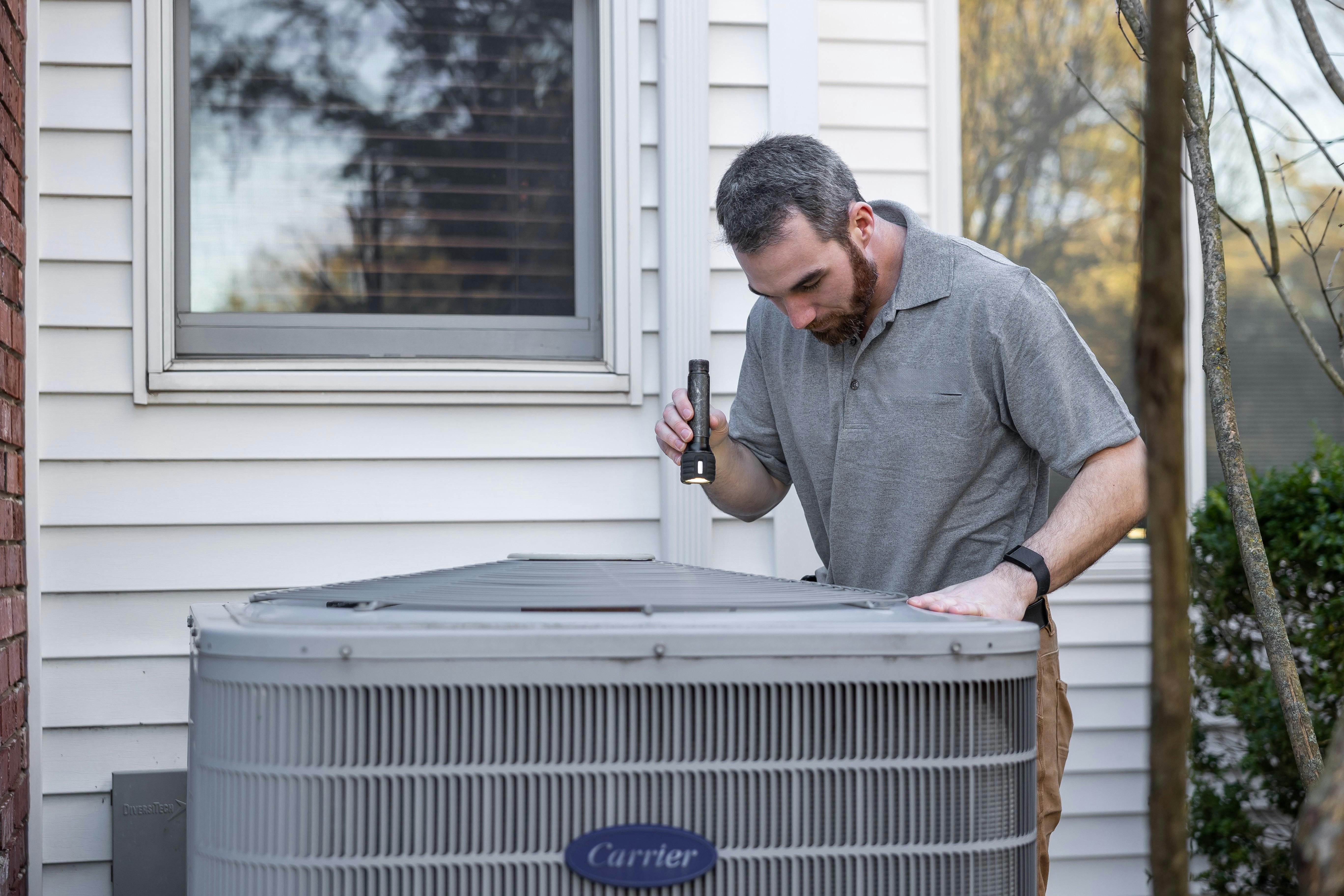 HVAC technician working on residential Carrier unit in Wasilla